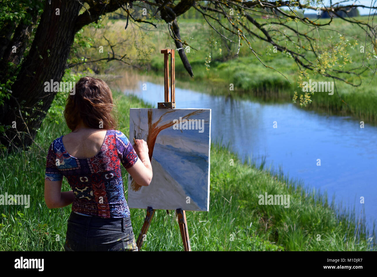 Paysage féminin artiste peint une belle petite scène de rivière sur toile. Banque D'Images