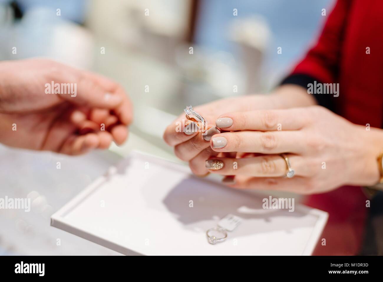 Vendeur féminin dans un magasin de bijoux de luxe présente un anneau. L' achat d'une bague de fiançailles. Magasin de bijoux. Femme bijoutier Photo  Stock - Alamy