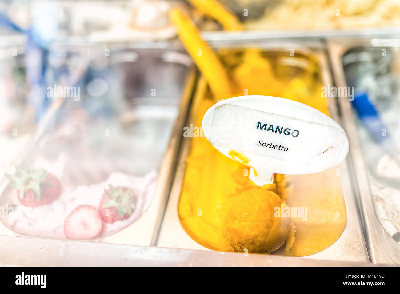 Gros plan macro de saveur mangue sorbet orange jaune crème glacée à signer sur l'affichage en magasin cafe shop avec écope en Italie, l'Italien sorbetto Banque D'Images