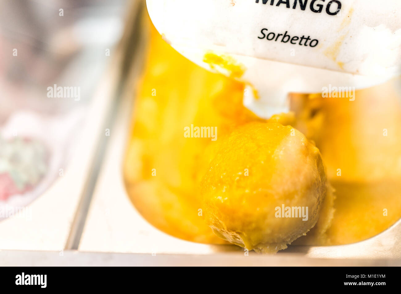 Gros plan macro de saveur mangue sorbet orange jaune crème glacée à signer sur l'affichage en magasin cafe shop avec écope en Italie, l'Italien sorbetto Banque D'Images