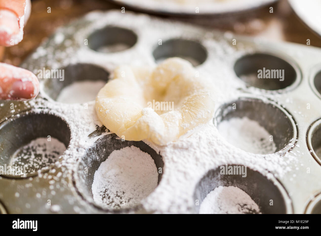 Mains, morceau de gâteau de riz gluant gluant mochi saupoudrée de farine pour faire de l'amidon en étain à muffin dessert Banque D'Images