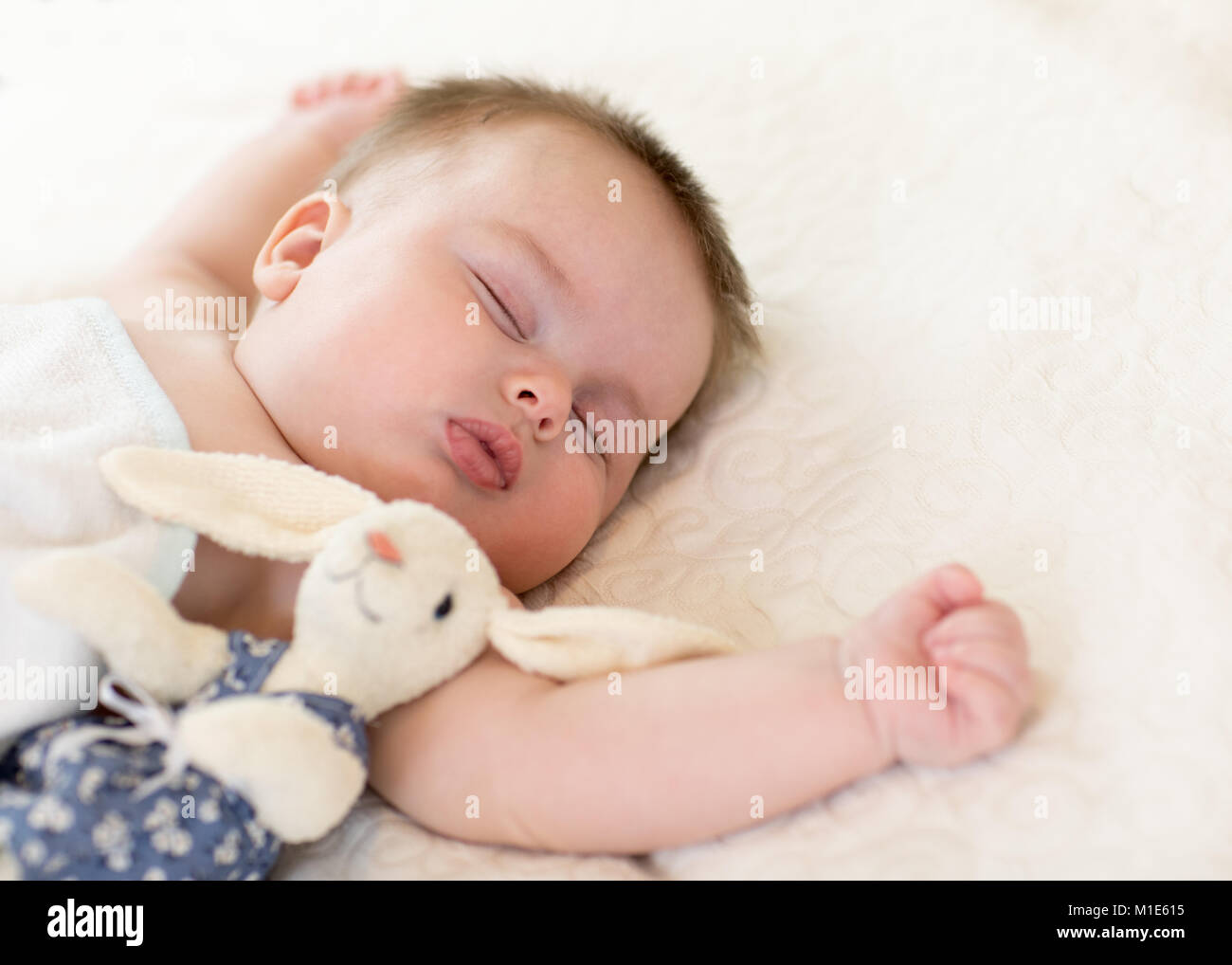 Mignon nouveau-né avec toy bunny sleeping on bed at home Banque D'Images