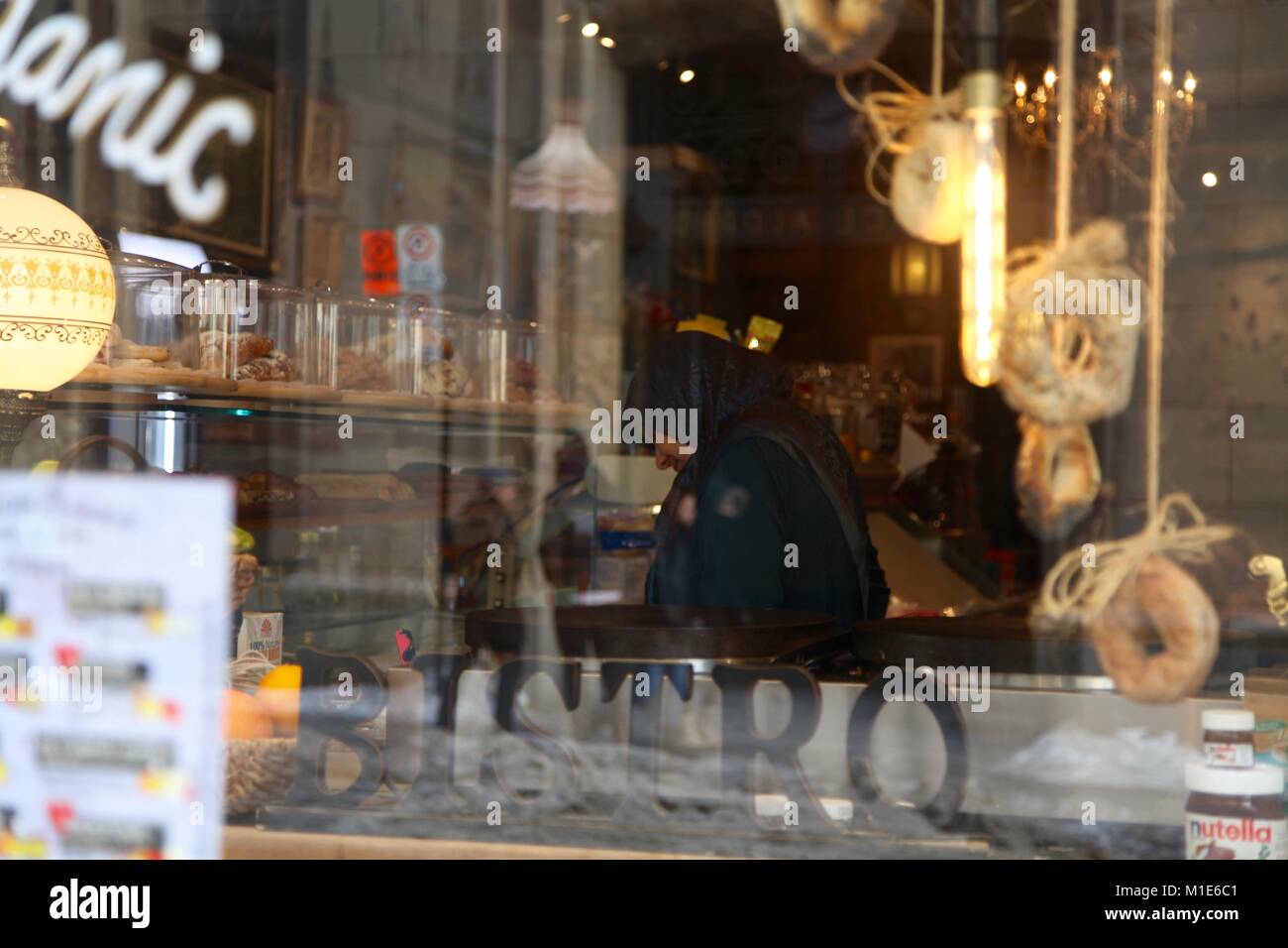 Jeune femme immigrante dans un hijab travaillant derrière un comptoir d'une boulangerie à Montréal, Canada Banque D'Images