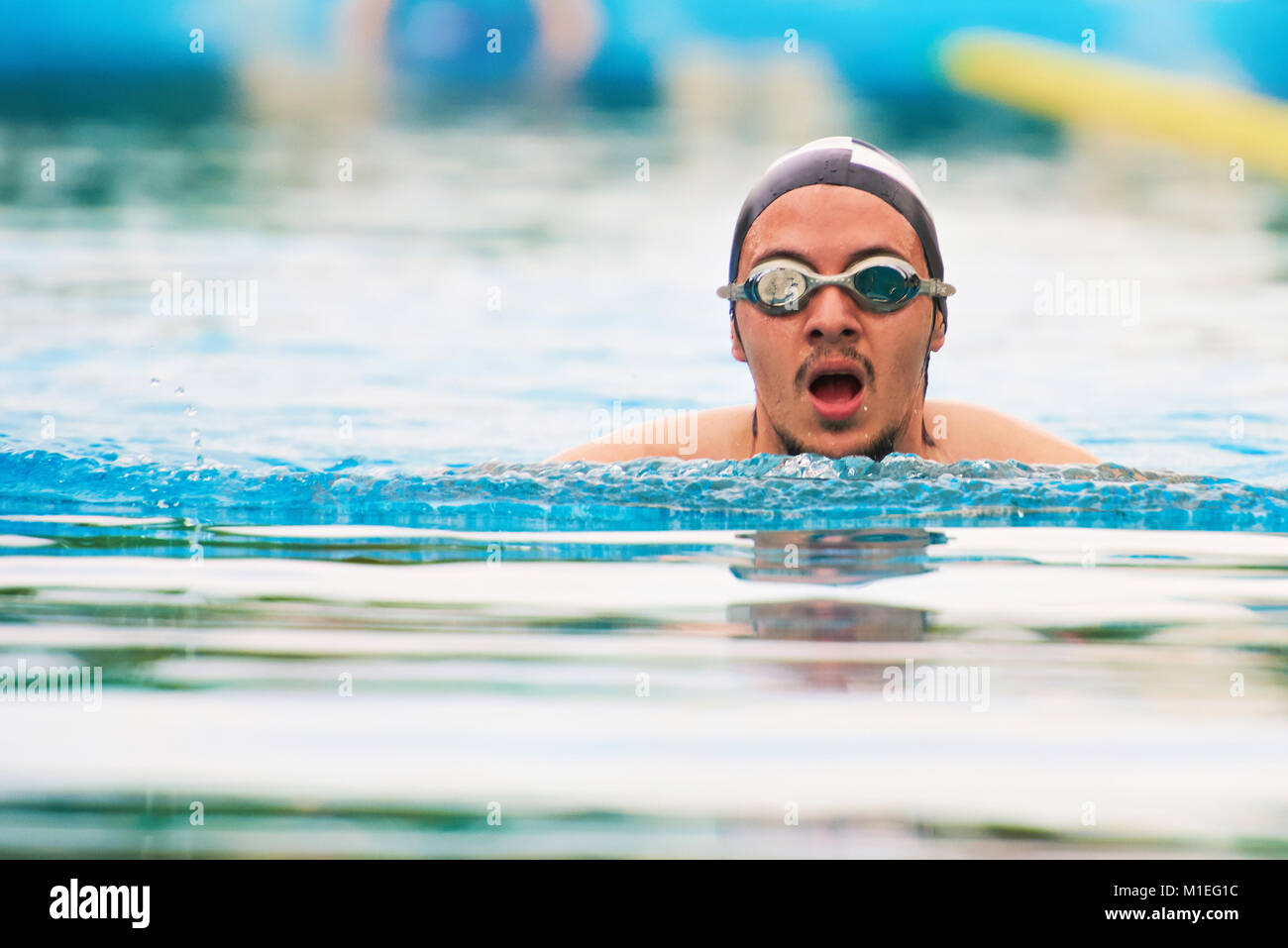 Man swimming in pool en lunettes et chapeau en caoutchouc Banque D'Images