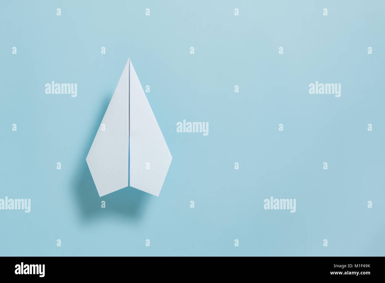 Mise à plat de l'avion en papier blanc sur fond de couleur bleu pastel Banque D'Images