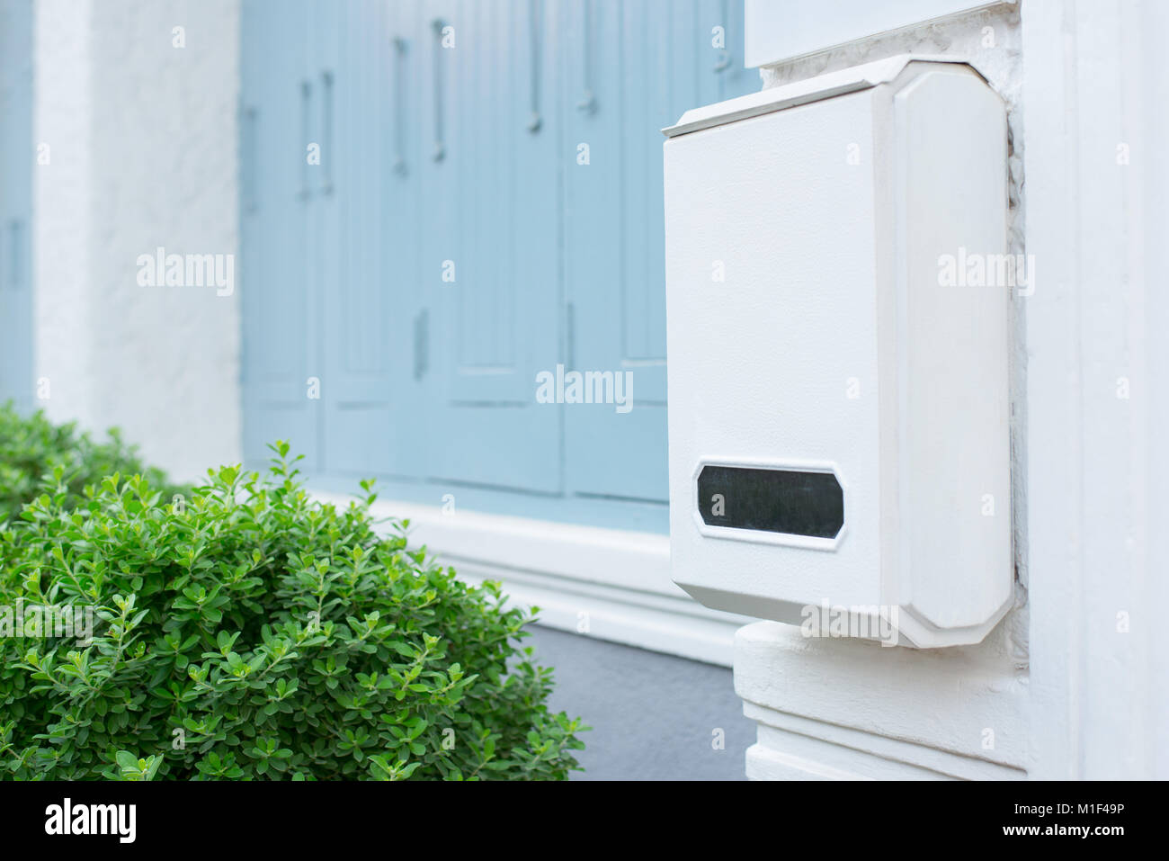 Post box sur mur blanc avec la nature verte, boîte aux lettres blanche Banque D'Images