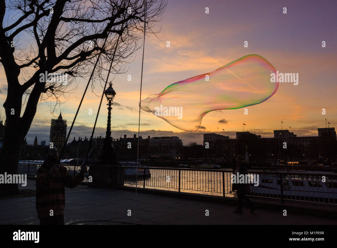 South Bank, Londres, Royaume-Uni, le 30 Jan 2018. Jake, un Bubble maker ou bubbler comme il préfère qu'on l'appelle, divertit les Londoniens sur la rive sud avec énorme, luminously bulles colorées comme le coucher de soleil sur la Tamise, le London Eye, Westminster et South Bank. Credit : Imageplotter News et Sports/Alamy Live News Banque D'Images