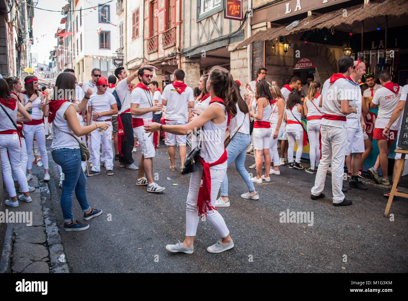 Des gens habillés en blanc et rouge boire et danser dans les rues à l'occasion de la fête d'été des fêtes de Bayonne (Bayonne), France Banque D'Images