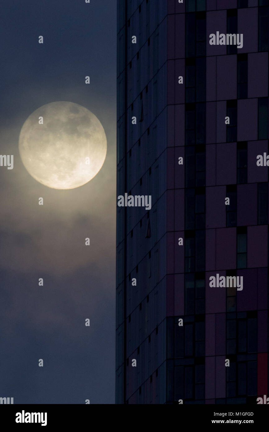 La lune s'élève derrière le bâtiment de la place Saffron à Croydon, devant un événement céleste « inhabituel », mercredi soir, lorsqu'une lune bleue se lève dans le ciel pour la première fois depuis juillet 2015. Banque D'Images