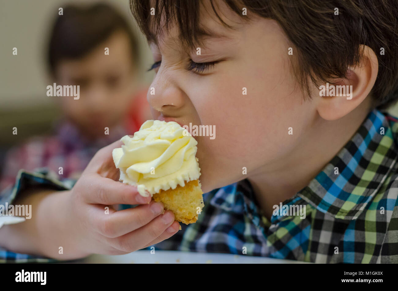 Un gros plan d'un jeune garçon de manger un cupcake. Banque D'Images