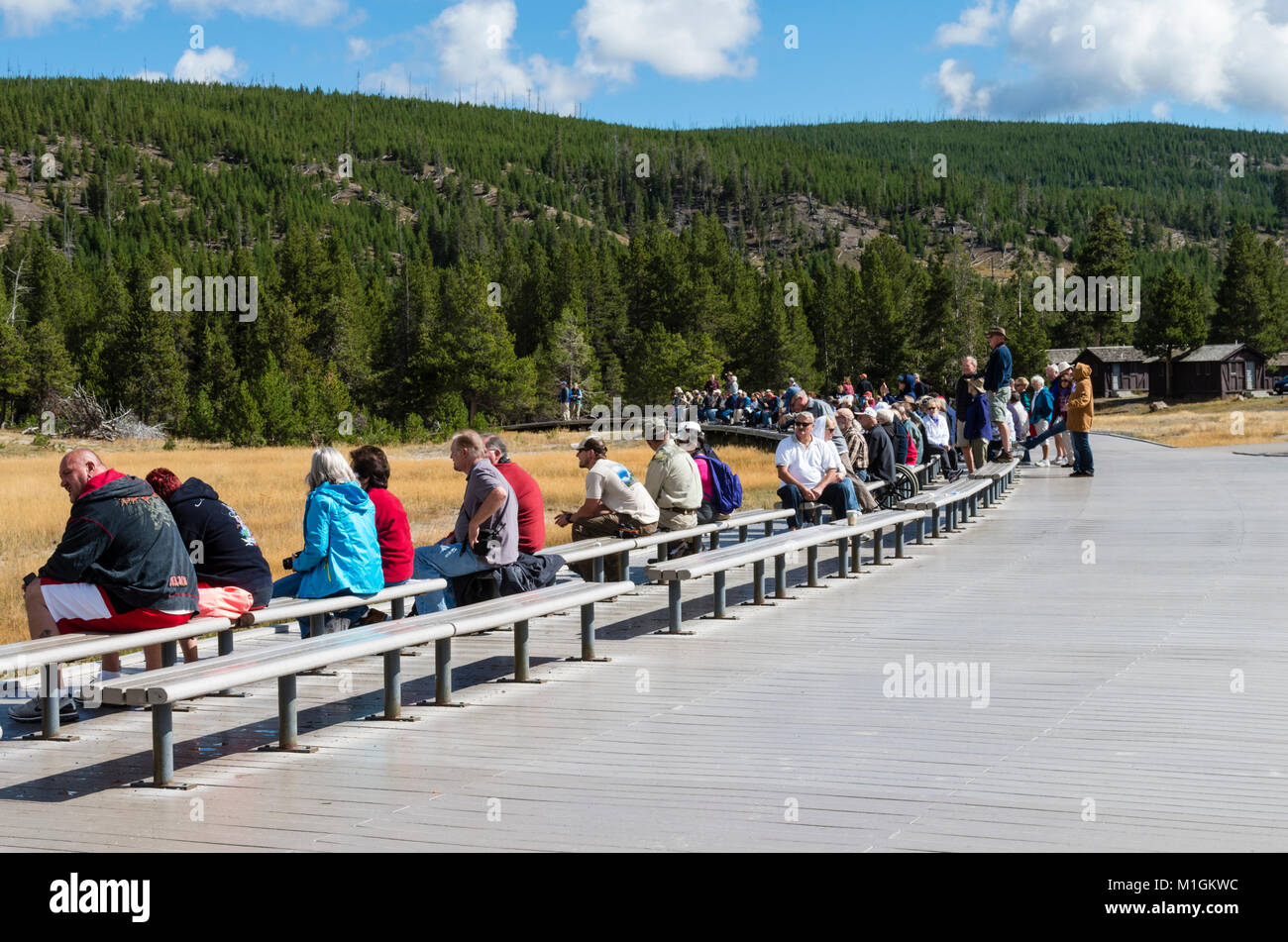 Les touristes assis sur des bancs en attente d'Old Faithful Geyser. Le Parc National de Yellowstone, Wyoming, USA Banque D'Images