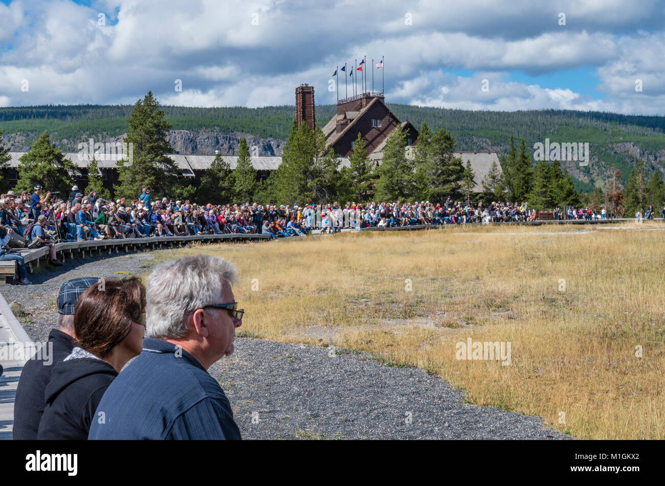 Les touristes assis sur des bancs en attente d'Old Faithful Geyser. Le Parc National de Yellowstone, Wyoming, USA Banque D'Images