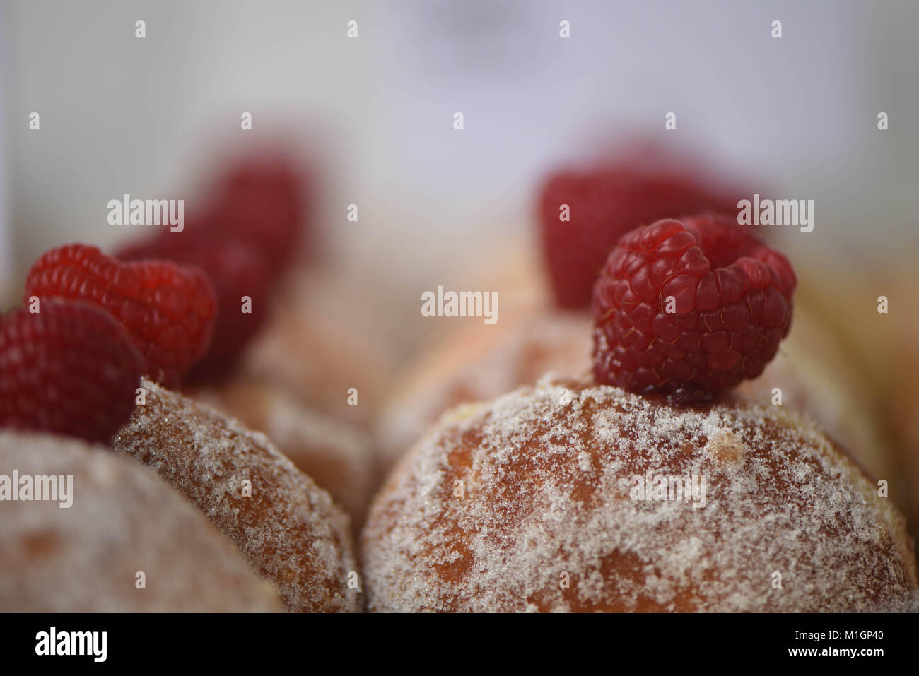 Droit de certains frais maison délicieux donuts ou beignets enrobés de sucre avec un remplissage de bourrage et surmonté d'un rouge juteux de framboise Banque D'Images