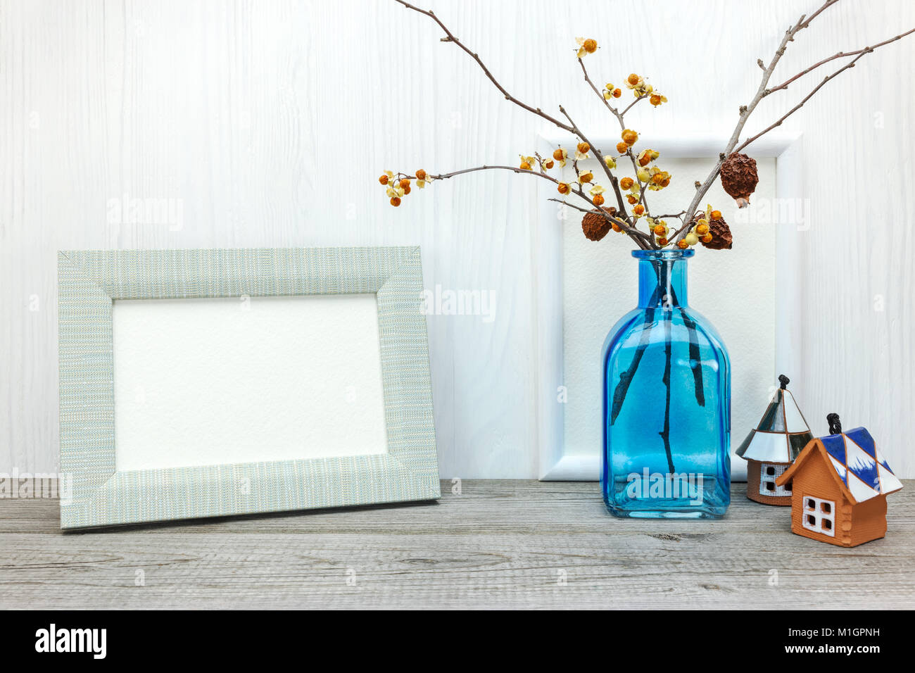 Cadre photo vide et bleu vase avec fleurs séchées sur fond de bois blanc Banque D'Images