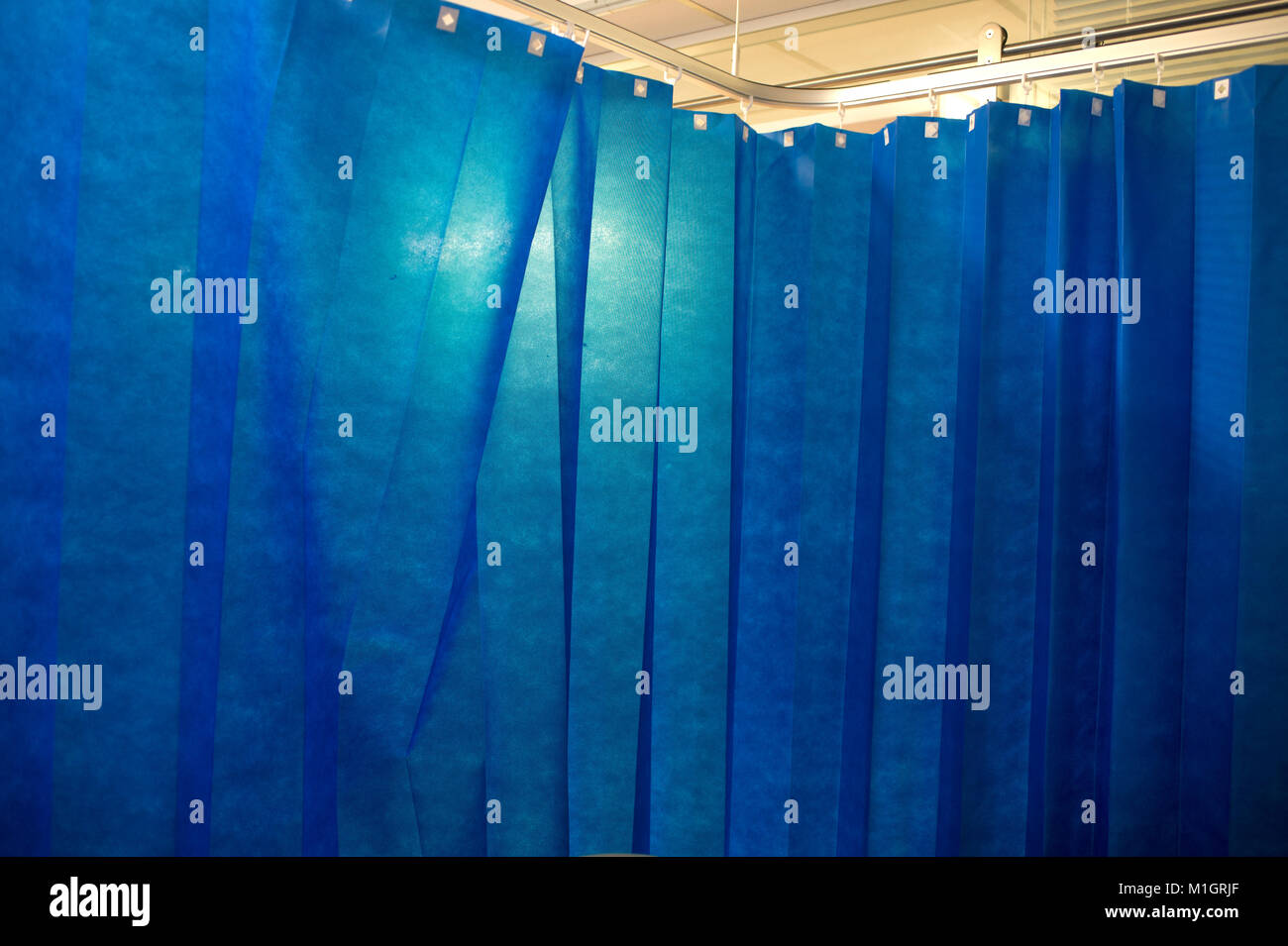 Hôpital du NHS. Rideaux bleus entourent un lit. Banque D'Images