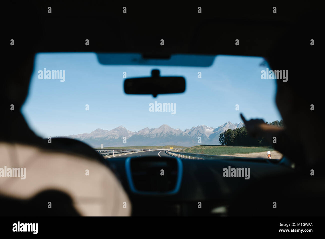 Couple au volant d'une voiture à la montagne - femme pointant sur les montagnes de l'intérieur d'une voiture. Banque D'Images