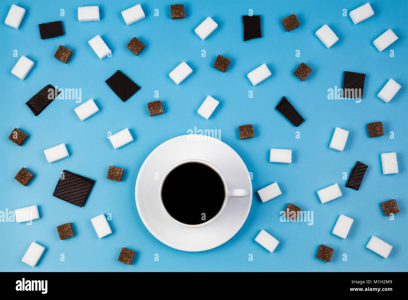 Tasse de café blanc, brun et blanc des morceaux de sucre et de chocolat prieces sur fond bleu Banque D'Images