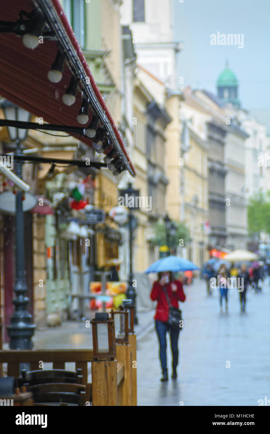 Rue de la ville européenne, la pluie, personne floue avec parapluie et mouchoir Banque D'Images