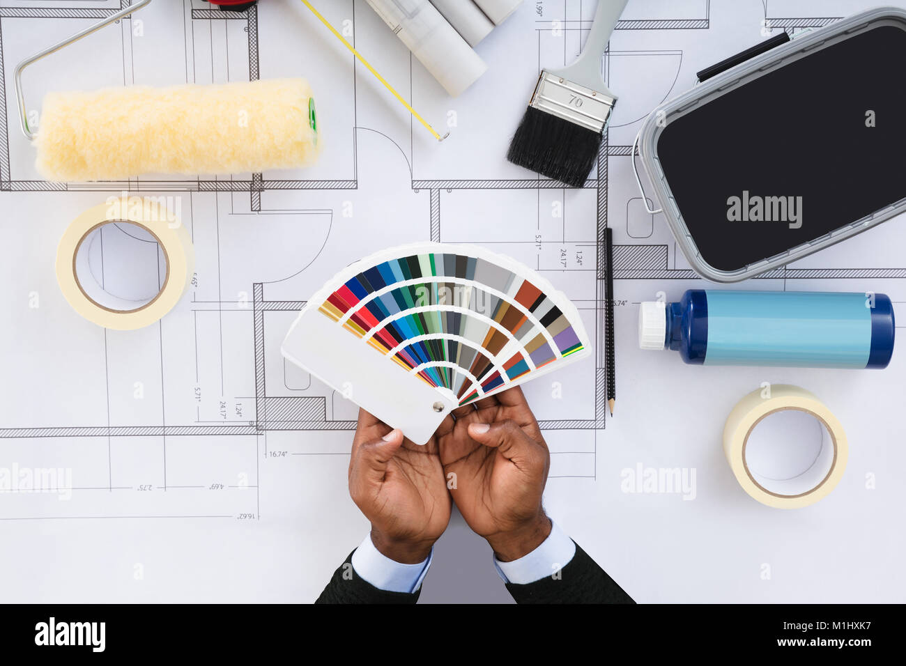 Portrait de la personne qui détient les échantillons de couleur contre l'équipement de peinture avec Blueprint Banque D'Images