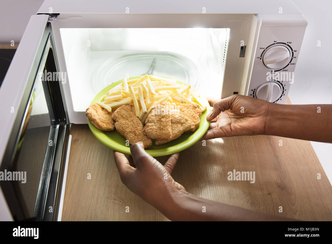 Close-up of a person's Hand Chauffage Les aliments frits dans un four micro-ondes four Banque D'Images