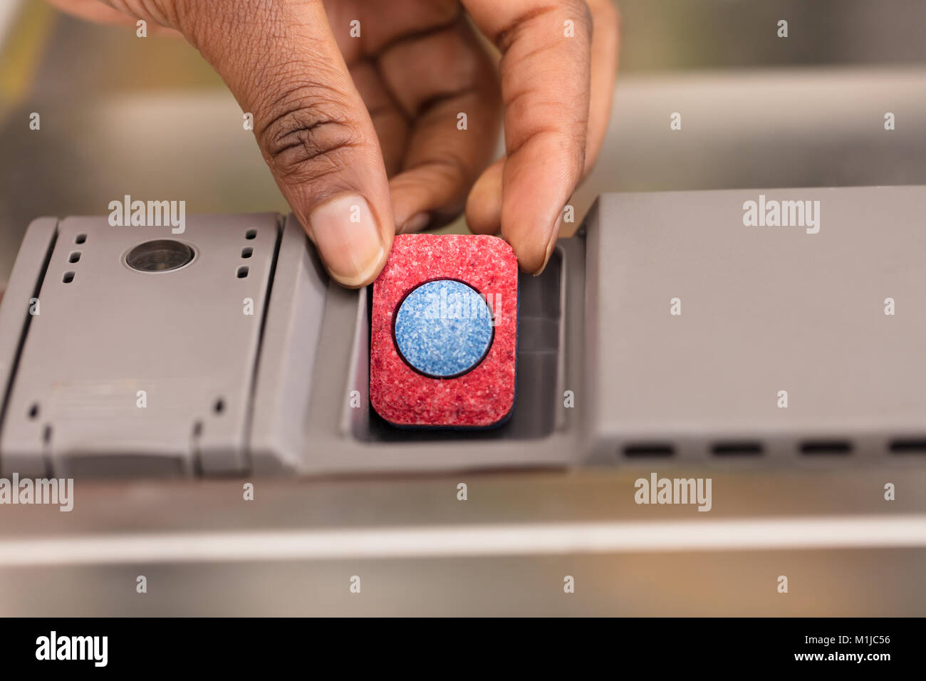 Close-up d'une main humaine la mise en tablette du savon lave-vaisselle fort Banque D'Images