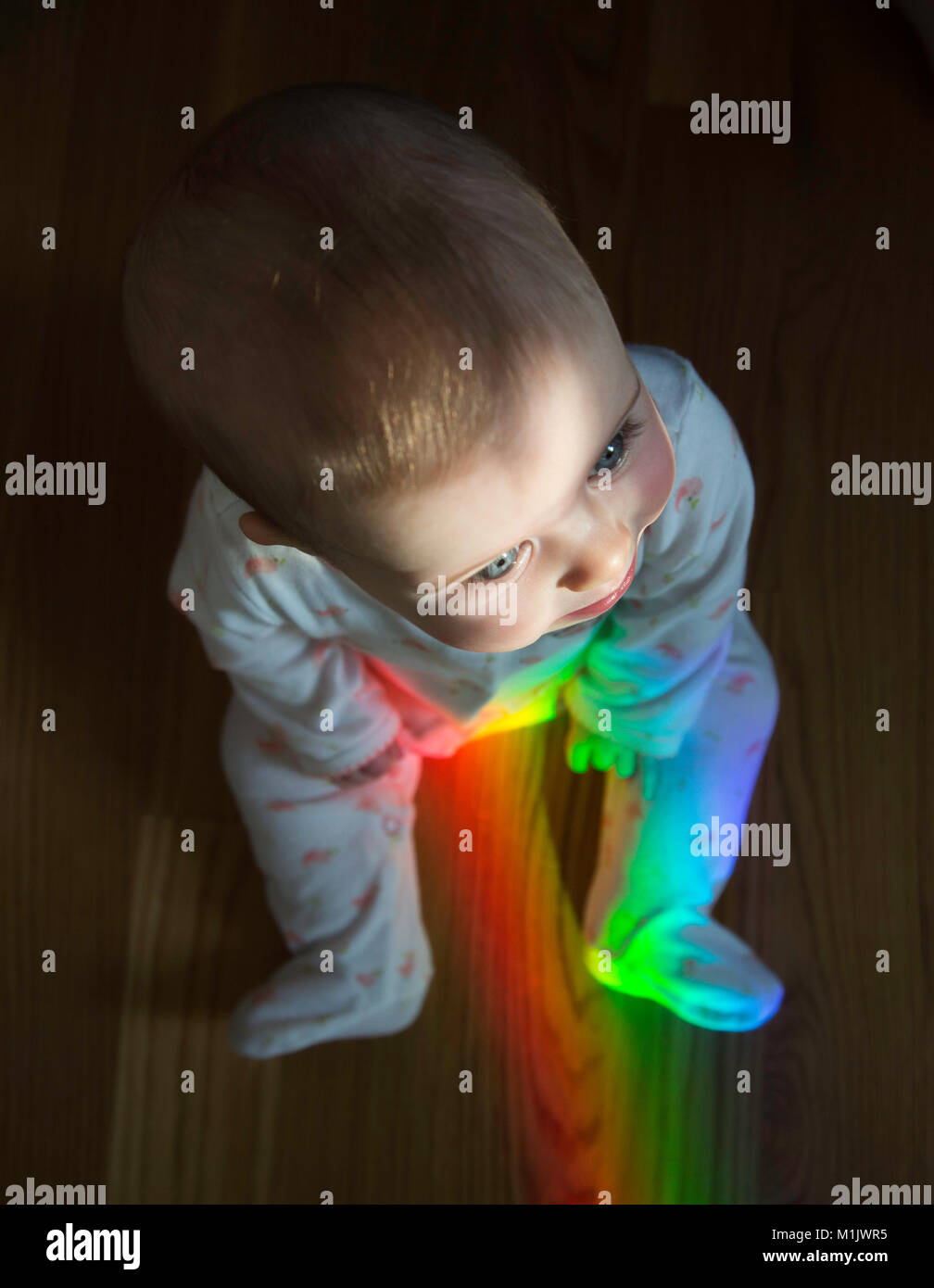 High Angle View of Baby Sitting on floor with Rainbow Banque D'Images