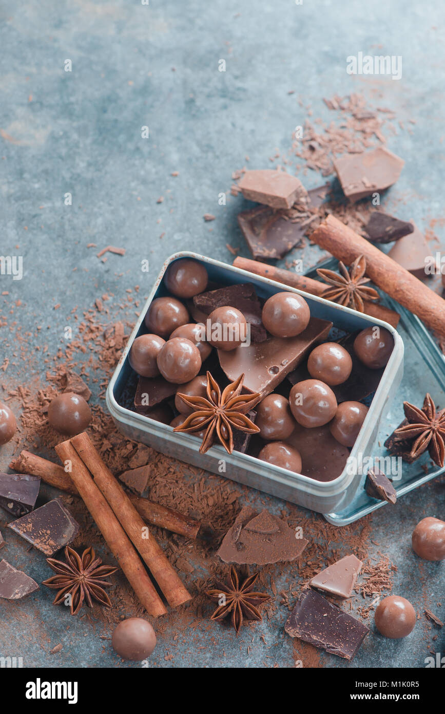 Boîte avec un assortiment de chocolats et des morceaux de chocolat cassé avec des épices, l'anis étoile, la cannelle et cacao sur un fond de pierre. Sucré fait maison Banque D'Images