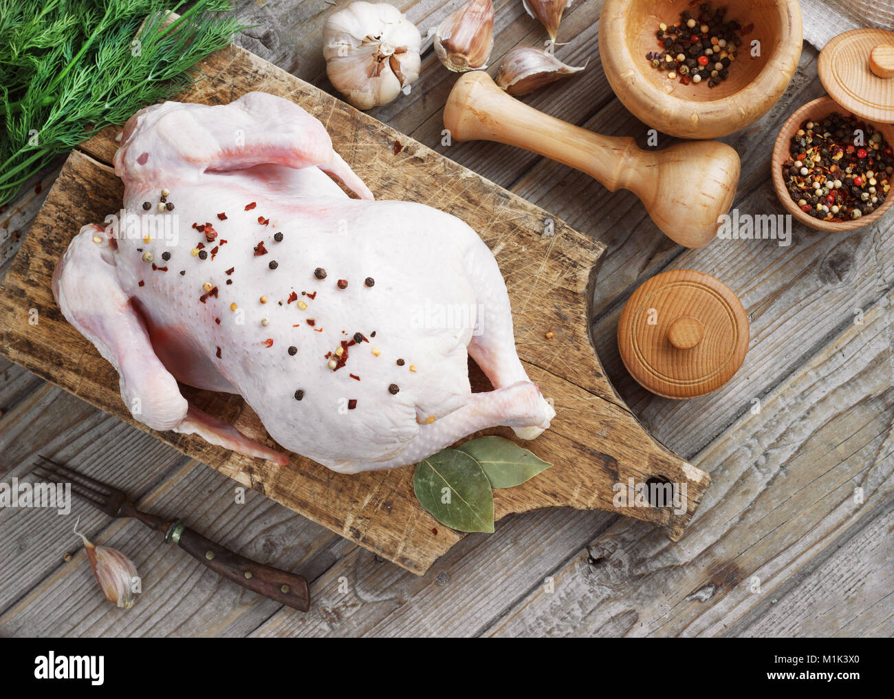 Carcasse de poulet sur un fond de bois avec des épices, la cuisine dans la cuisine, style rustique. Banque D'Images