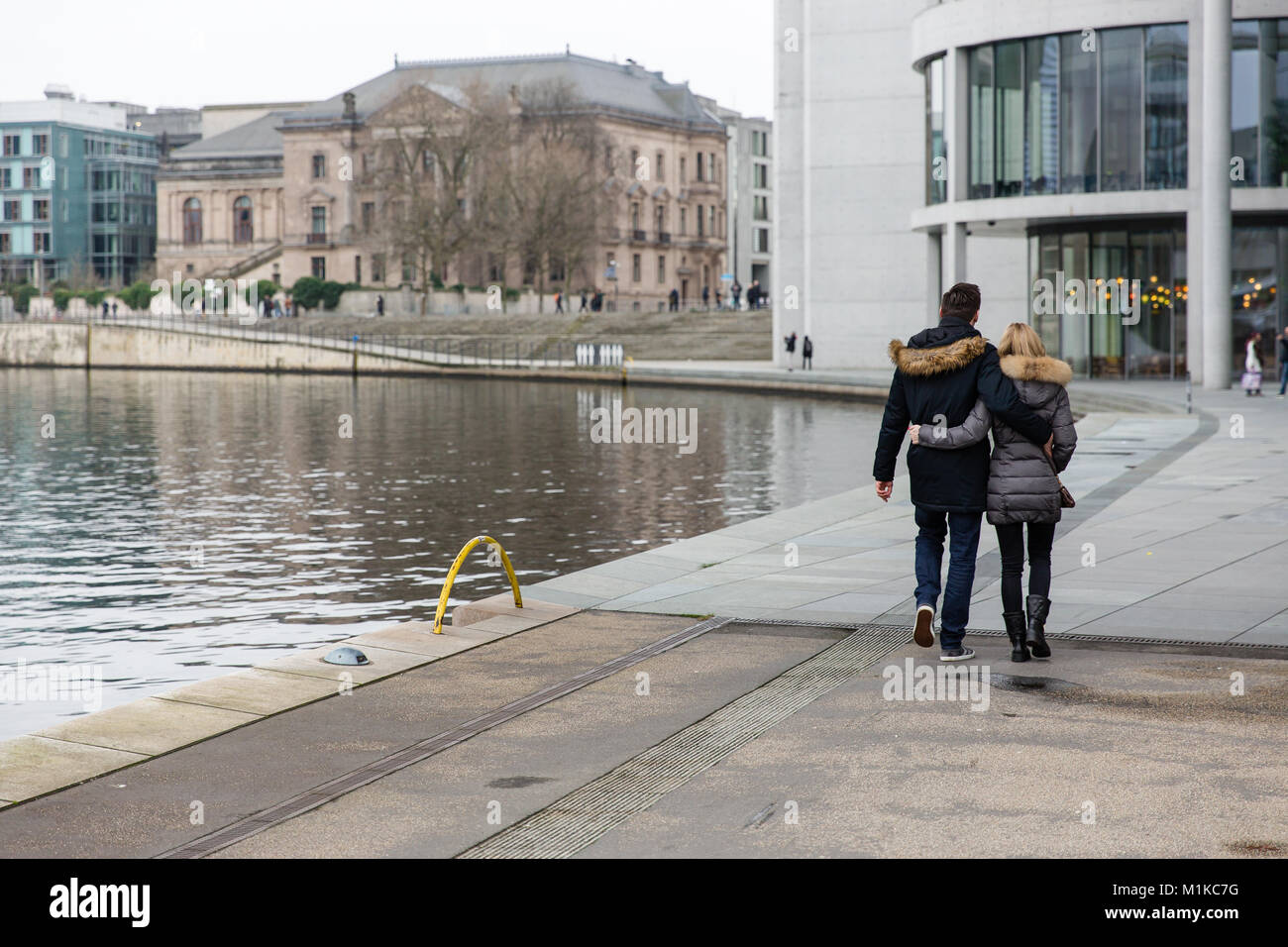 Couple en train de marcher le long de la rivière Spree entouré par l'architecture moderne du quartier du gouvernement de Berlin la capitale allemande Banque D'Images