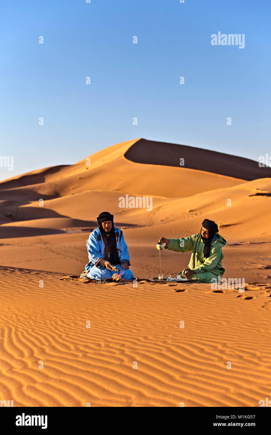 Le Maroc, Mhamid, Erg Chigaga dunes de sable. Désert du Sahara. Les nomades Berbères la préparation du thé et parler. Banque D'Images