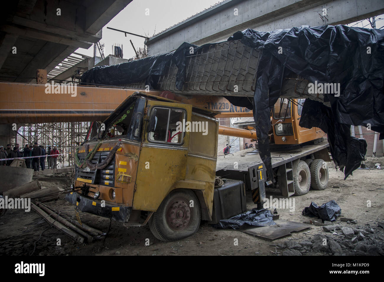 31 janvier 2018 - Srinagar, Jammu-et-Cachemire, l'Inde - les gens regardent une poutre caisson allongé sur un véhicule endommagé après qu'elle est tombée d'un pont en construction suite à un puissant séisme a frappé le nord de l'Afghanistan avec des tremblements d'avis aussi largement que le Pakistan et le nord de l'Inde, le 31 janvier 2018 à Srinagar, la capitale d'été du Cachemire indien, l'Inde. L'ampleur 6.1 séisme a été centrée dans les montagnes de l'Hindu Kush région, l'US Geological Survey a signalé. Une jeune fille a été tué et cinq autres blessés dans le village de Lasbela dans la province du Balouchistan au Pakistan lors de la ro Banque D'Images