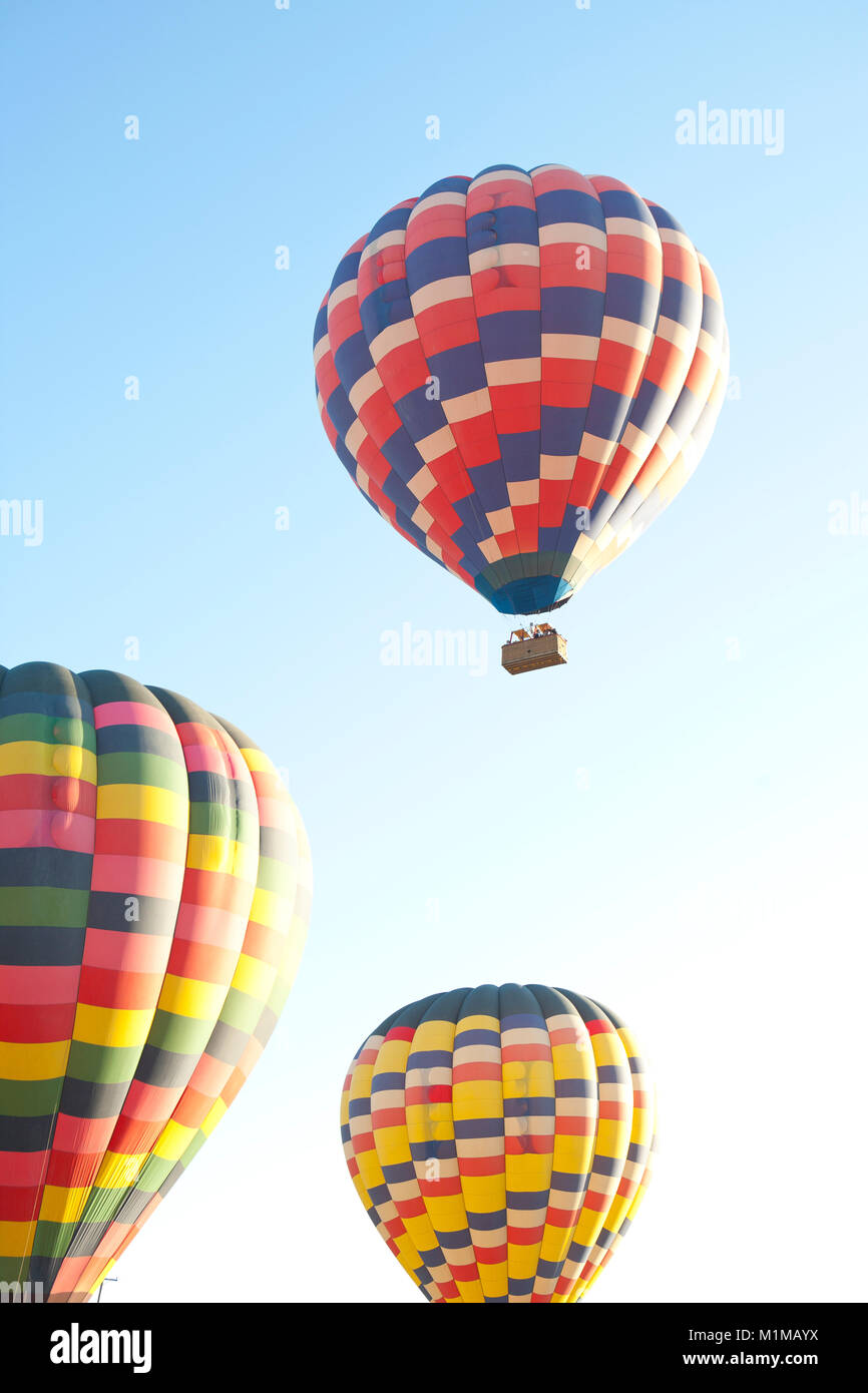 Montgolfières en vol avec des couleurs vibrantes contre tôt le matin, ciel bleu Banque D'Images