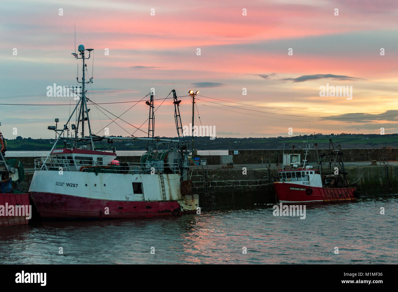 Les chalutiers et bateaux de pêche amarrés au coucher du soleil dans le port de Duncannon, comté de Wexford, Irlande avec copie espace. Banque D'Images