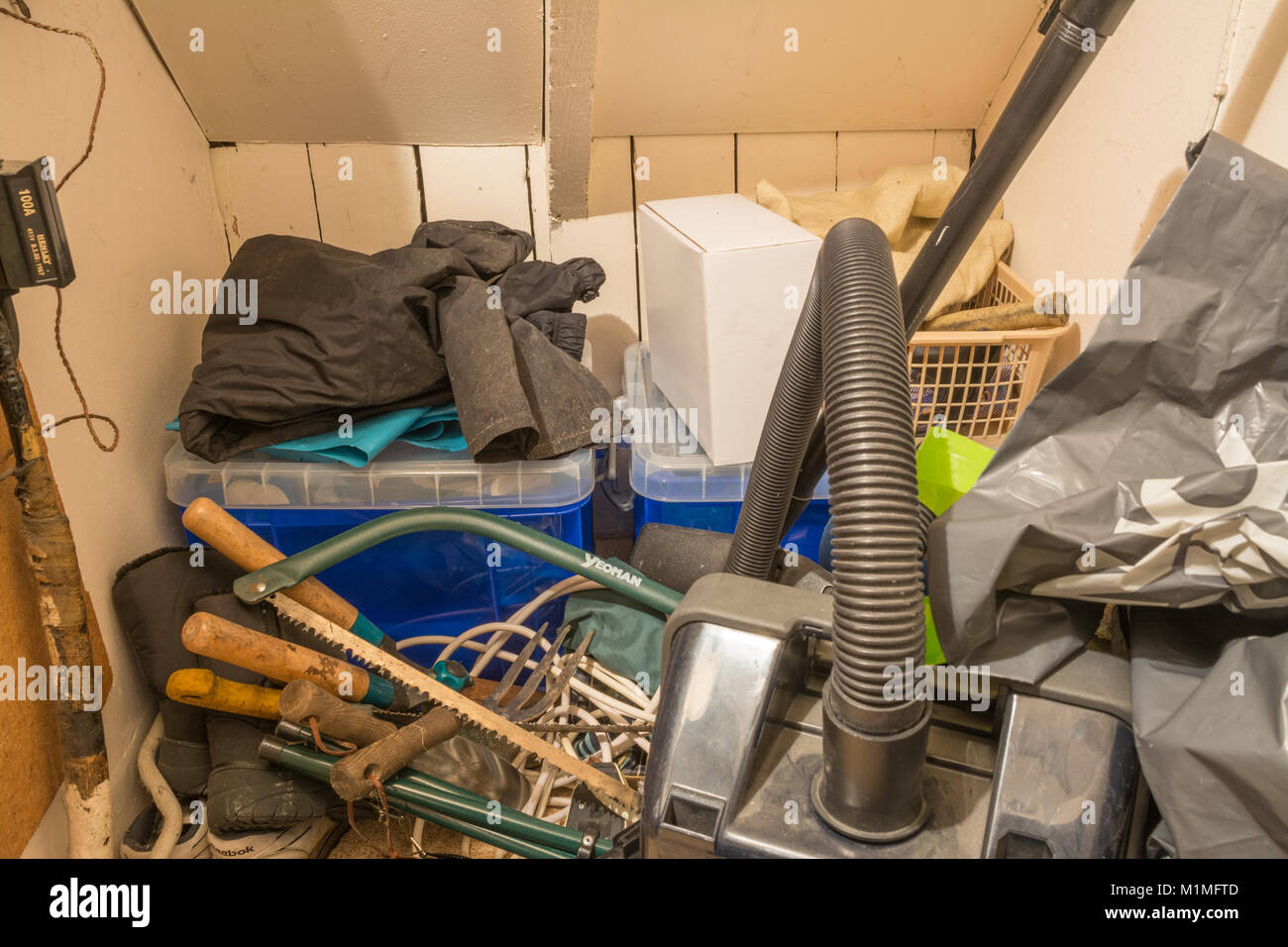 Sous les escaliers placard plein d'objets quotidiens, y compris des outils, aspirateur, boîtes de rangement et l'encombrement Banque D'Images