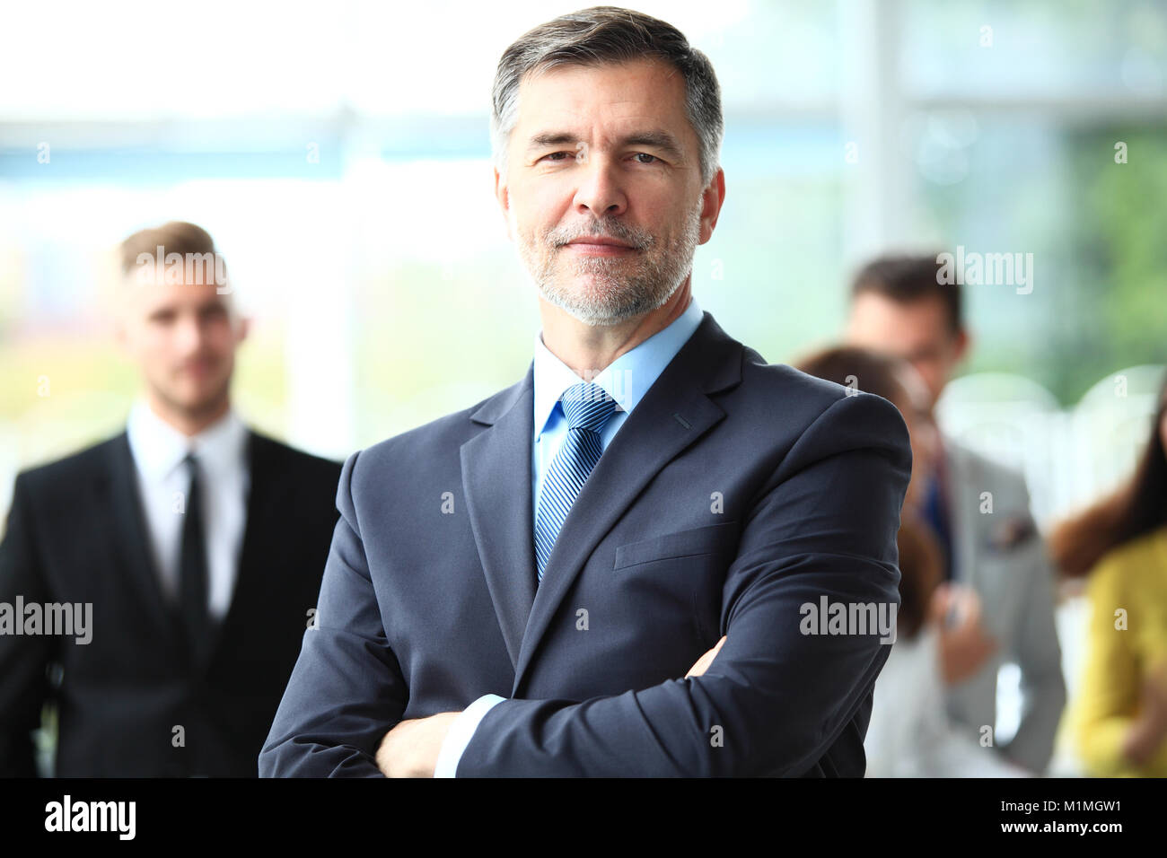 Smiling mature business manager croisant les bras en face de son équipe commerciale. Banque D'Images