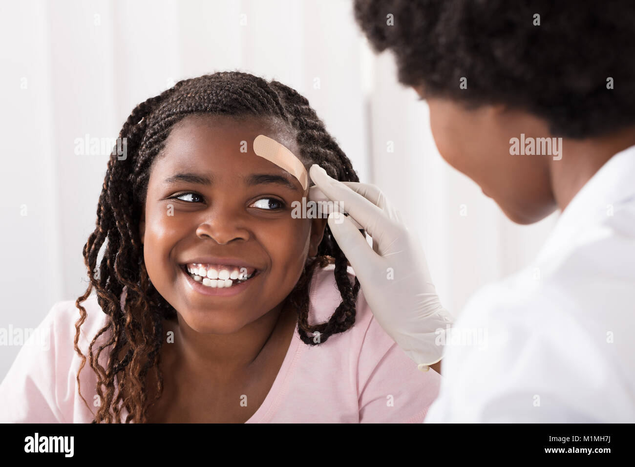 Close-up d'un médecin d'appliquer à l'aide de bande Girl Head en clinique Banque D'Images