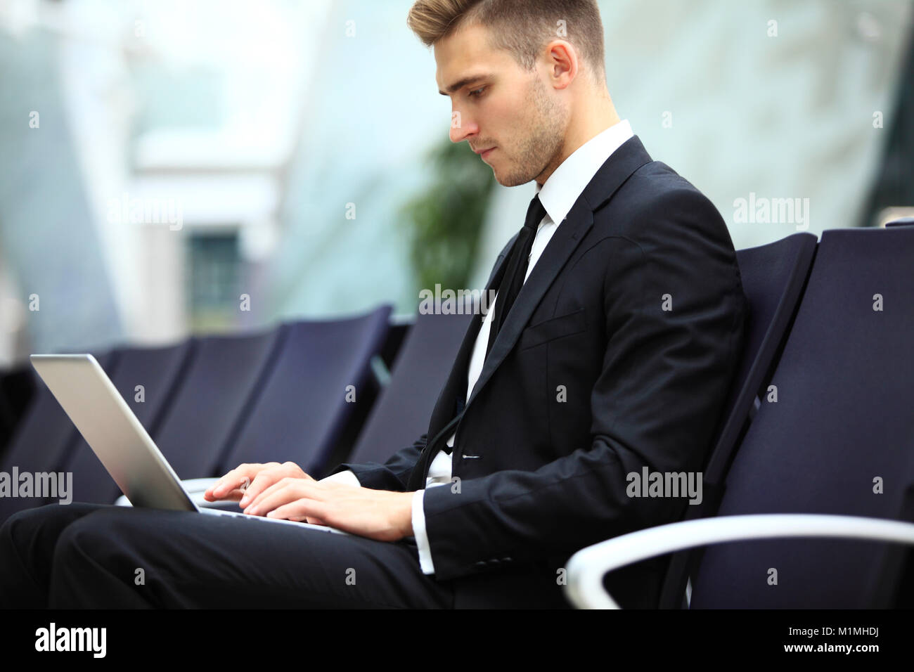 Young adult using laptop in airport lounge Banque D'Images