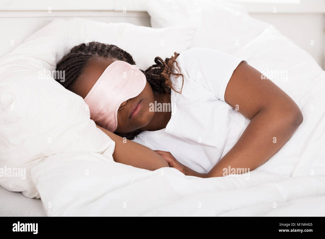 Close-up of an African Girl with Pink Eye Mask Sleeping In Bed Banque D'Images