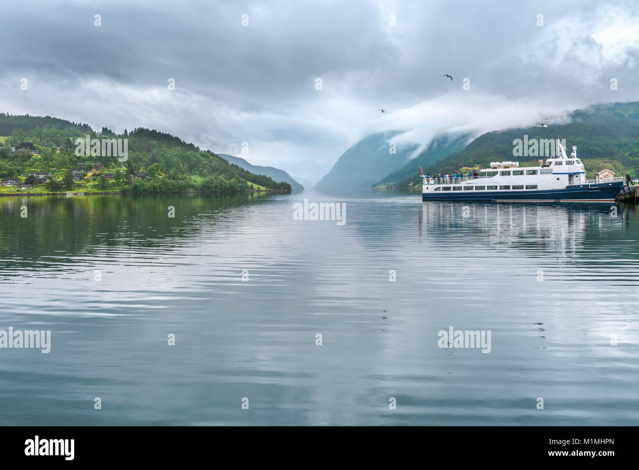 Un ferry et le fjord à Ulvik, Norvège, Scandinavie, Ulvikafjorden, comté de Hordaland, Wallonie, avec ses montagnes couvertes de nuages Banque D'Images