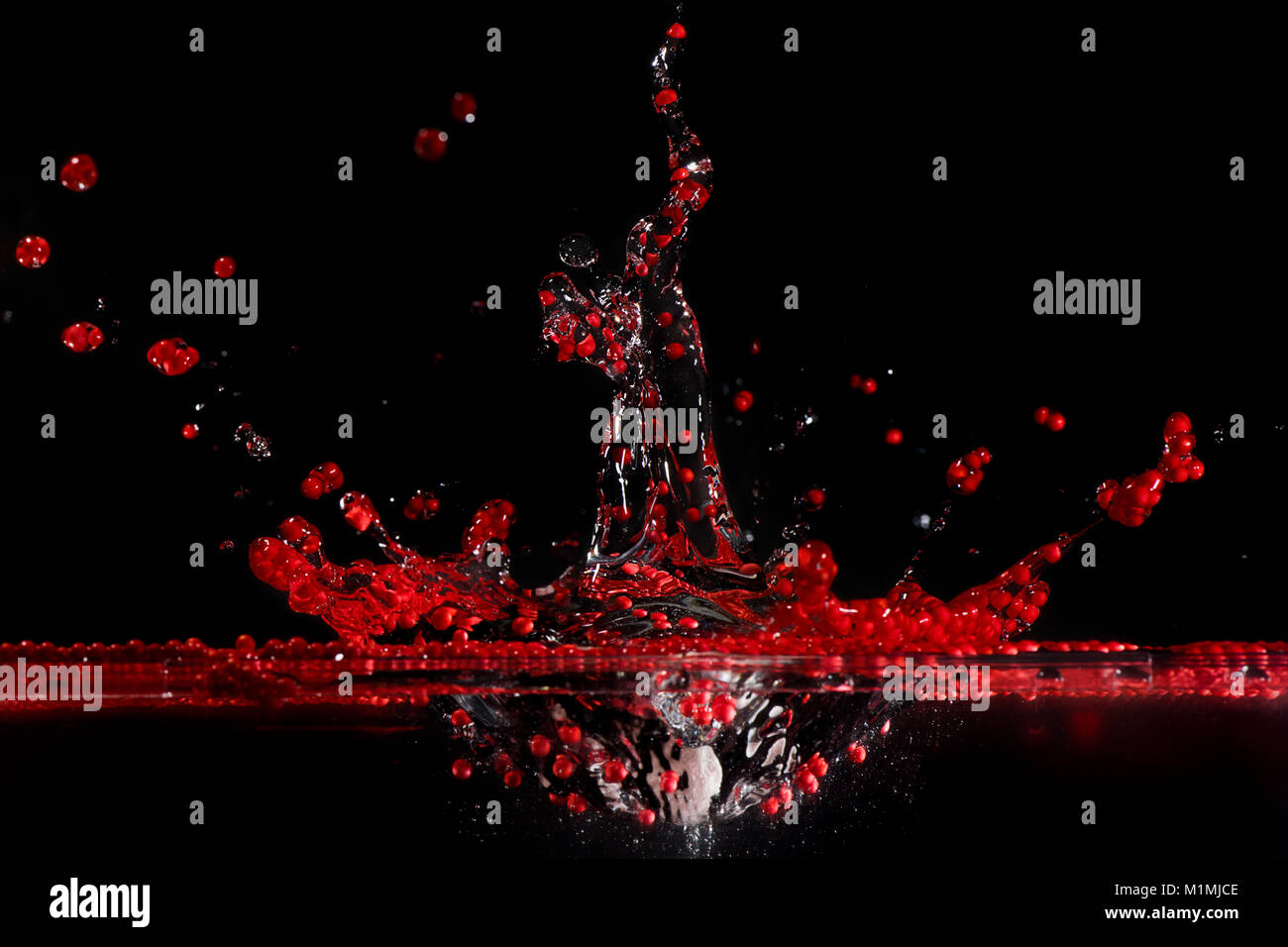 Des sphérules de polystyrène rouge splashing in water Banque D'Images