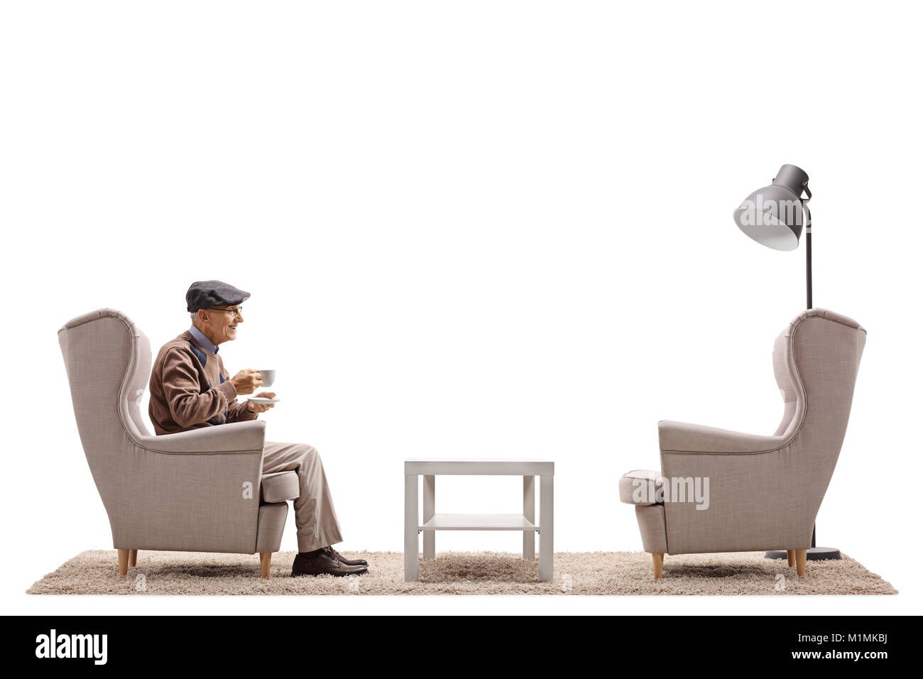 Un homme âgé avec une tasse assise sur un fauteuil isolé sur fond blanc Banque D'Images