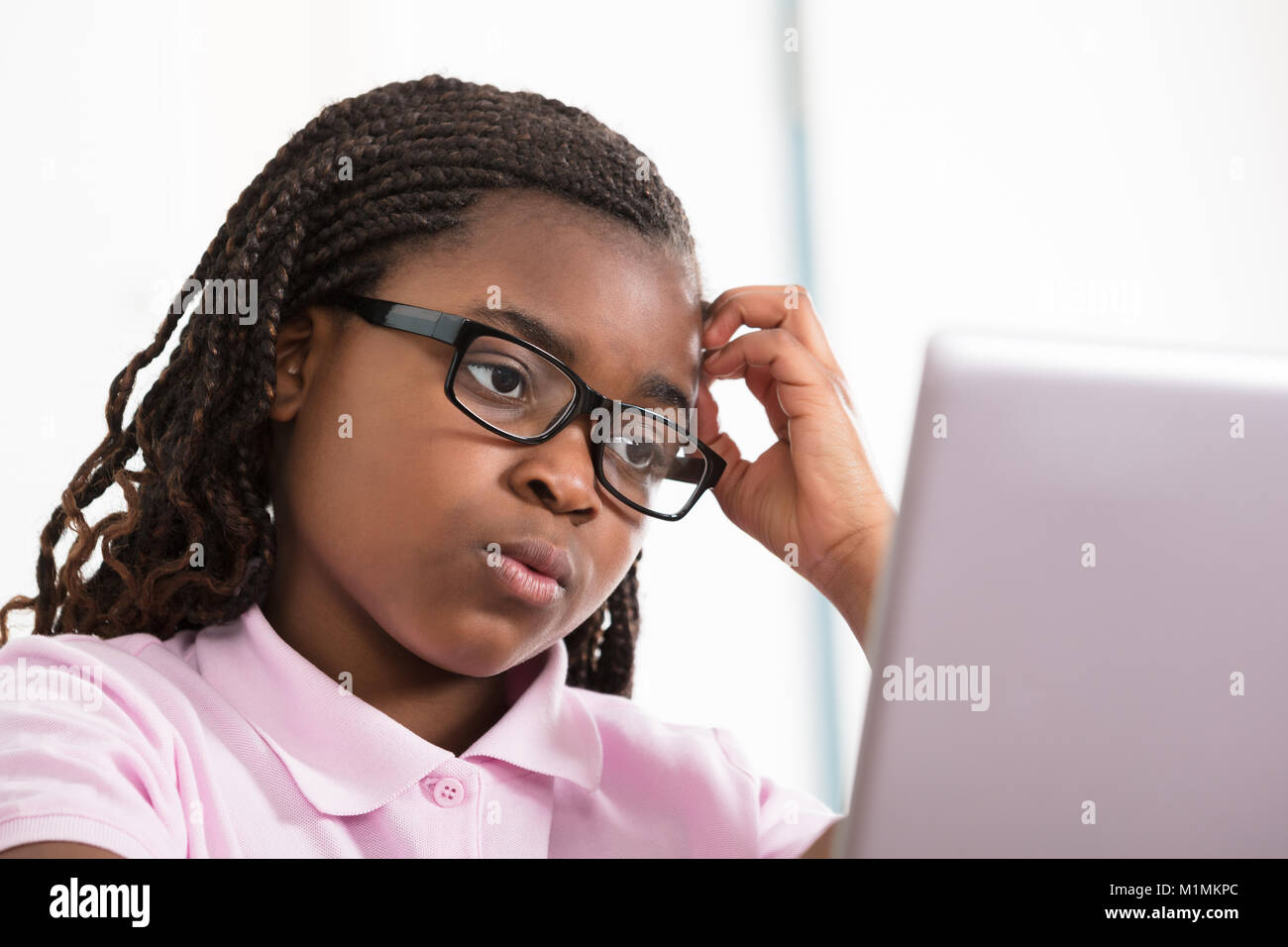 Fille envisagée avec lunettes Looking At Laptop Banque D'Images