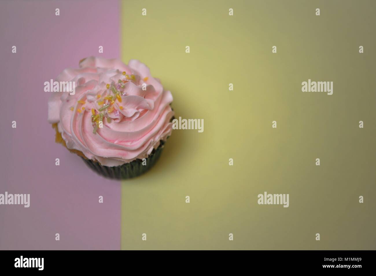 Fait main délicieux cupcake rose swirl avec glaçage glacé sur le dessus avec un fond de couleur pastel ton split et l'espace Banque D'Images