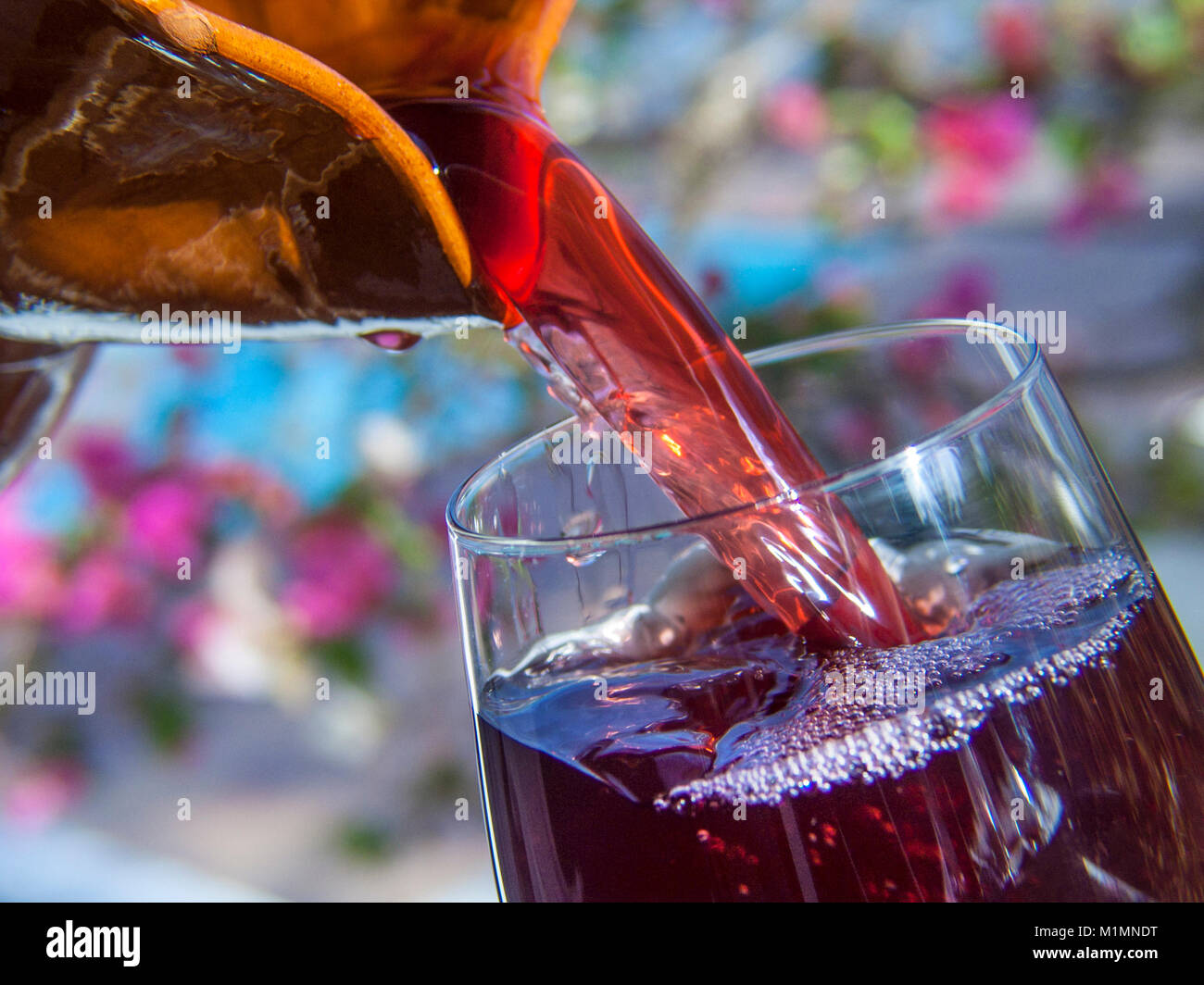 Pichet Sangria Sangria Alfresco FLEURS ESPAGNE verseur à vin rouge de la terre cuite dans un verre à vin avec holiday villa bougainville jardin fleurs et piscine en arrière-plan Canaries Espagne Banque D'Images