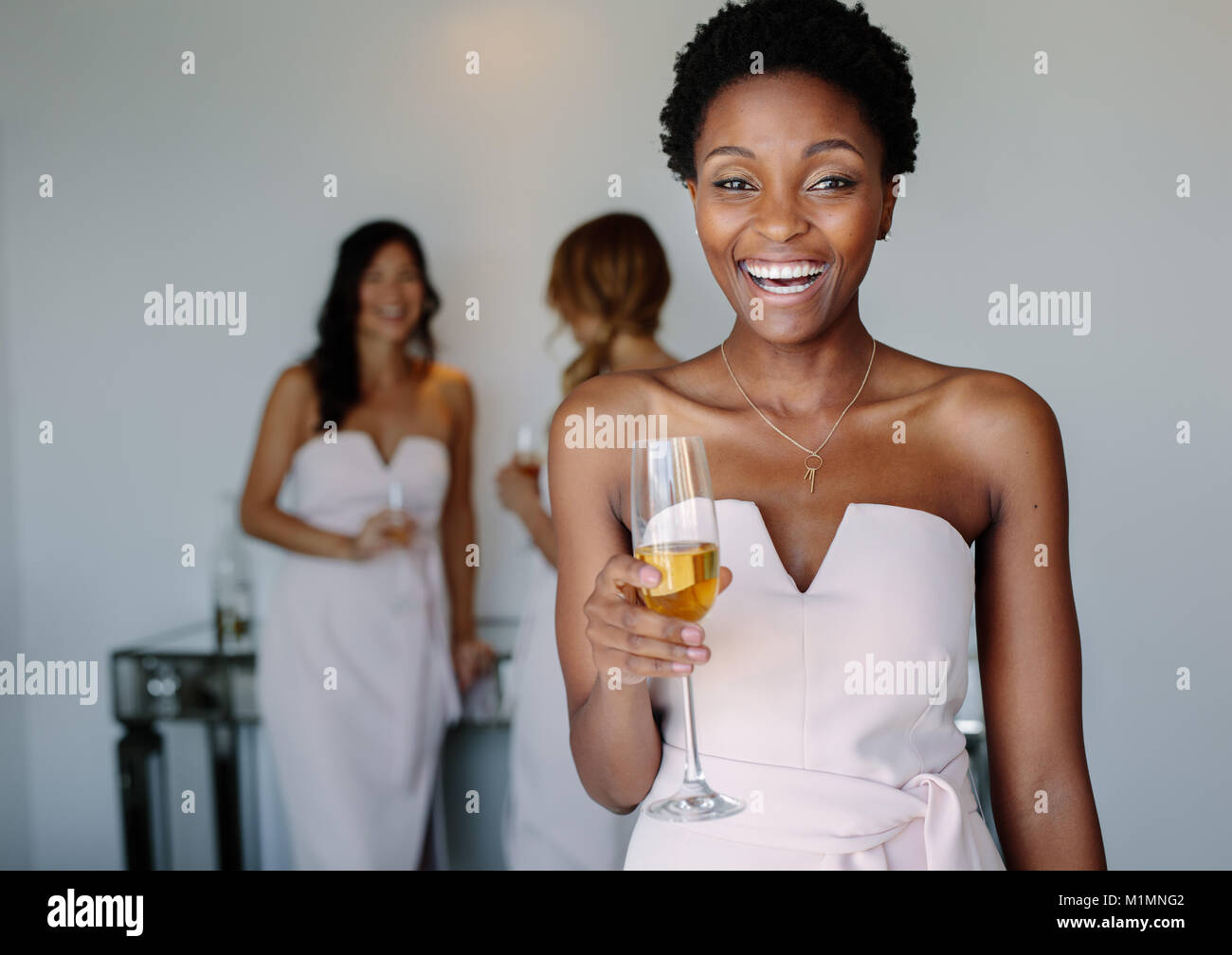 Belle jeune demoiselle d'avoir du vin à jour du mariage. Smiling african woman having drinks dans une chambre d'hôtel. Banque D'Images