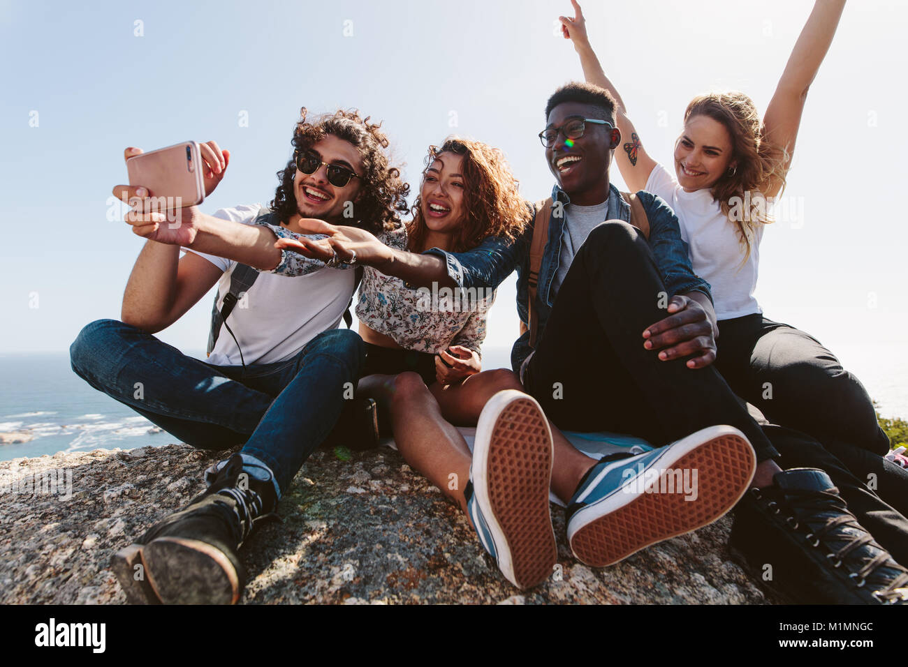 Amis assis au sommet d'une montagne en tenant. selfies Groupe d'hommes et de femmes assis sur le dessus d'une colline et décisions. selfies Banque D'Images