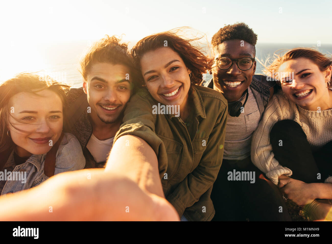 Cheerful friends en prenant des vacances. selfies Groupe d'hommes et de femmes assises à l'extérieur, sur une journée d'été faire de l'auto portrait. Banque D'Images