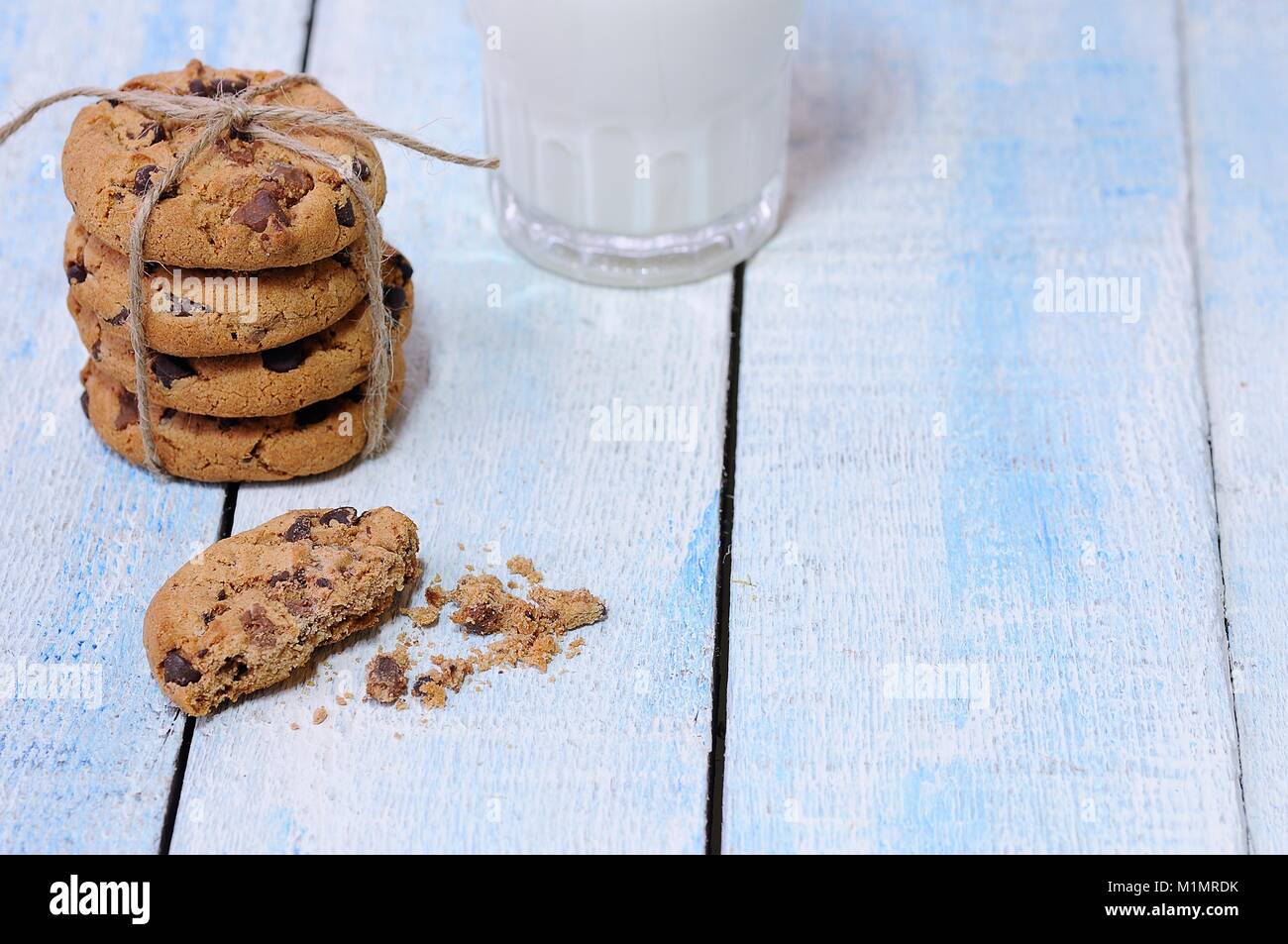 Pile de cookies aux pépites de chocolat avec un verre de lait frais sur la table en bois bleu Banque D'Images