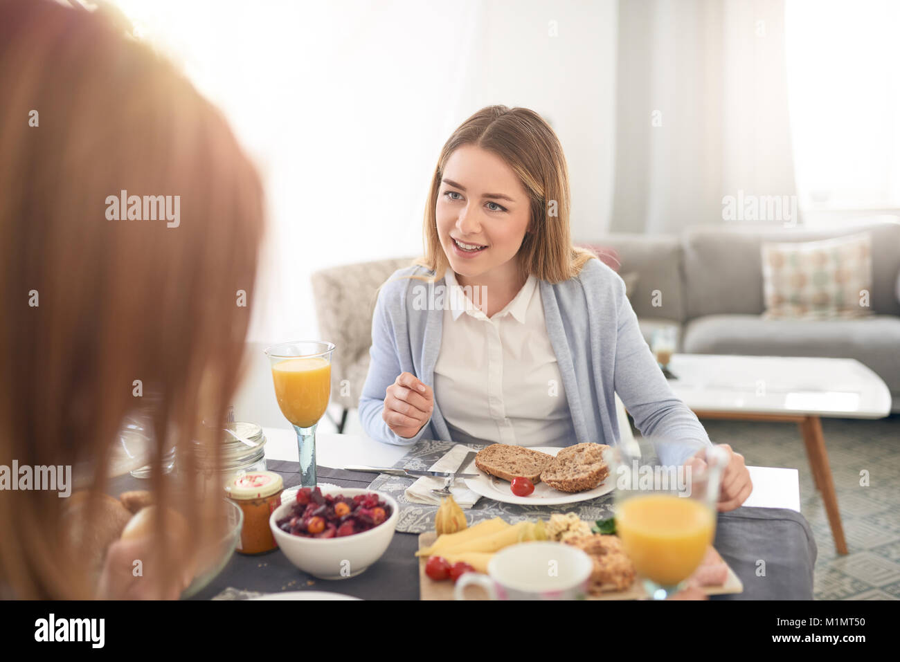 Attractive young woman sitting écoute attentivement sa mère comme ils bénéficient du temps de qualité ensemble plus d'un copieux petit-déjeuner dans un s Banque D'Images