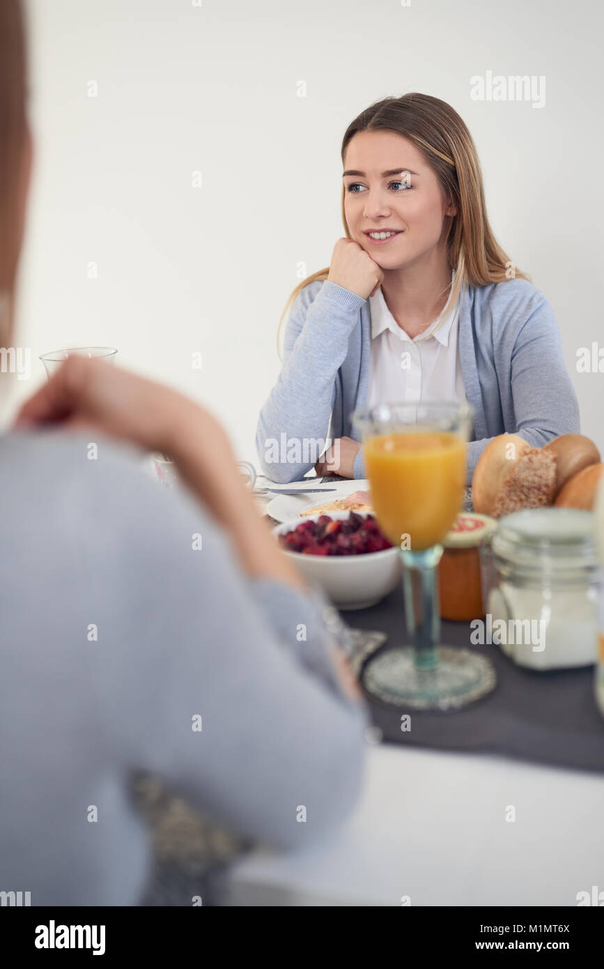 Attractive young woman sitting écoute attentivement sa mère comme ils bénéficient du temps de qualité ensemble plus d'un copieux petit-déjeuner dans un s Banque D'Images